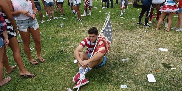 A soccer fan sits on the ground during a viewing party at Veteran's Park in Redondo Beach, California July 1, 2014 after Belg