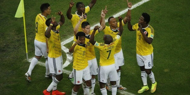 Colombia's midfielder James Rodriguez (C) is mobbed by teammates as he celebrates his second goal during the Round of 16 football match between Colombia and Uruguay at The Maracana Stadium in Rio de Janeiro on June 28, 2014,during the 2014 FIFA World Cup. AFP PHOTO / FABRIZIO BENSCH/POOL (Photo credit should read FABRIZIO BENSCH/AFP/Getty Images)