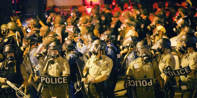 FERGUSON, MO - AUGUST 17: Police advance on demonstrators protesting the killing of teenager Michael Brown on August 17, 2014 in Ferguson, Missouri. Police shot smoke and tear gas into the crowd of several hundred as they advanced near the police command center which has been set up in a shopping mall parking lot. Brown was shot and killed by a Ferguson police officer on August 9. Despite the Brown family's continued call for peaceful demonstrations, violent protests have erupted nearly every night in Ferguson since his death. (Photo by Scott Olson/Getty Images)