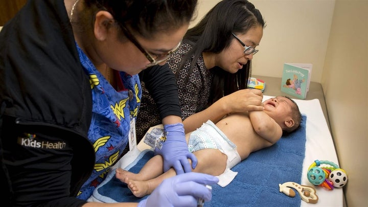 <p>A mother comforts her 6-month-old son as a medical assistant administers his immunizations in Springfield, Oregon, last month. Five states are working with the Centers for Disease Control and Prevention to improve vaccination rates. </p>