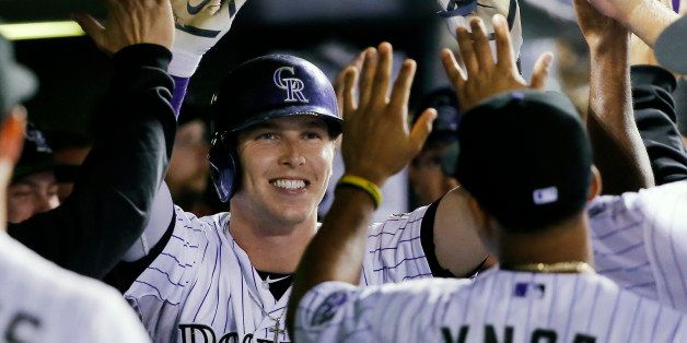 Colorado Rockies' Corey Dickerson is congratulated in the dugout by teammates after hitting a two run home run off Los Angeles Dodgers starting pitcher Dan Haren during the fourth inning of a baseball game Tuesday, Sept. 16, 2014, in Denver. (AP Photo/Jack Dempsey)