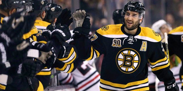 Boston Bruins center Patrice Bergeron, right, is congratulated by teammates after his goal against the Chicago Blackhawks during the first period of an NHL hockey game, Thursday, March 27, 2014, in Boston. (AP Photo/Charles Krupa)