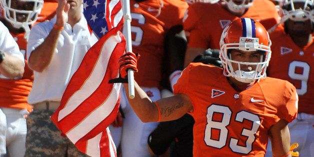 Army veteran and Clemson wide receiver Daniel Rodriguez (83) carries the American flag before an NCAA college football game against Virginia Tech on Saturday, Oct. 20, 2012, in Clemson, S.C. (AP Photo/Rainier Ehrhardt)