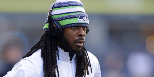 Seattle Seahawks cornerback Richard Sherman wears headphones as he walks on the field during warm-ups for the team's NFL foot