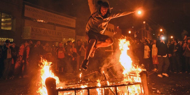 A man jumps over some debris that has been set on fire in the Mission district after the San Francisco Giants beat the Kansas City Royals to win the World Series on Wednesday, Oct. 29, 2014, in San Francisco. (AP Photo/Noah Berger)