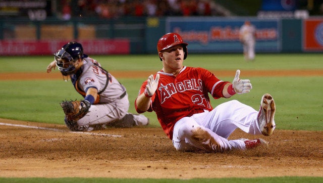 ANAHEIM, CA - SEPTEMBER 12: Mike Trout #27 of the Los Angeles Angels of Anaheim slides safely past catcher Jason Castro #15