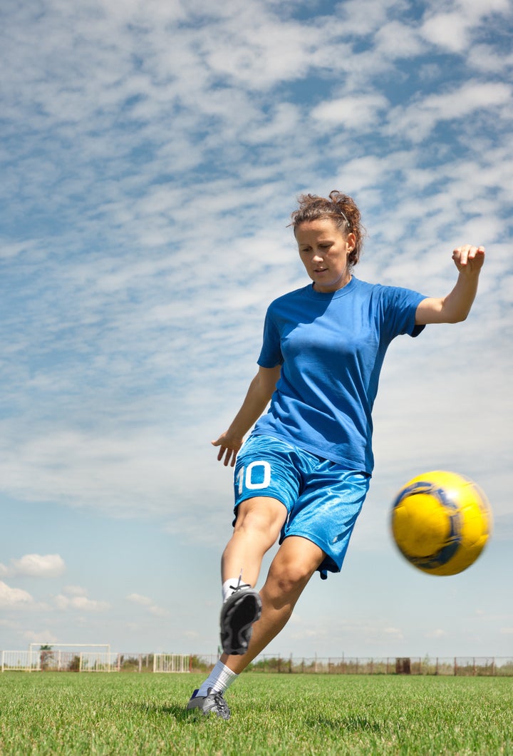 young girl kicking soccer ball...