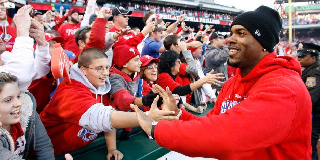 Philadelphia Phillies' Jimmy Rollins hi-fives fans lining the field at Citizen's Bank park at the end of the celebration of t