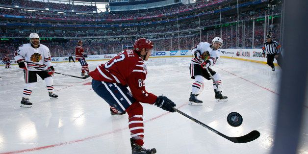 Washington Capitals center Jay Beagle (83) defends as Chicago Blackhawks defenseman Niklas Hjalmarsson (4), from Sweden, clears the puck in the third period of the Winter Classic outdoor NHL hockey game at Nationals Park, Thursday, Jan. 1, 2015, in Washington. The Capitals won 3-2. (AP Photo/Alex Brandon)