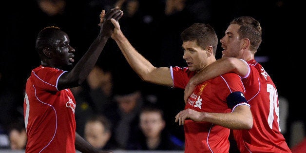 KINGSTON UPON THAMES, ENGLAND - JANUARY 05: Steven Gerrard of Liverpool is congratulated by teammates Mamadou Sakho (L) and Jordan Henderson (R) after scoring his team's second goal from a free kick during the FA Cup Third Round match between AFC Wimbledon and Liverpool at The Cherry Red Records Stadium on January 5, 2015 in Kingston upon Thames, England. (Photo by Michael Regan/Getty Images)