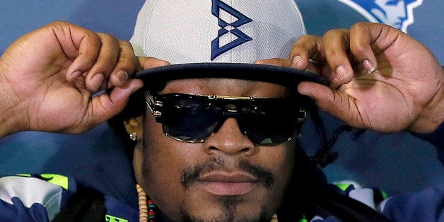 Seattle Seahawks' Marshawn Lynch adjusts his cap during an interview for the NFL Super Bowl XLIX football game, Thursday, Jan