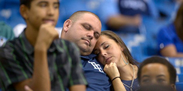 Two Tampa Bay Rays fans sleep in the stands during the 16th inning of a baseball game against the Baltimore Orioles in St. Petersburg, Fla., Saturday, Sept. 21, 2013.(AP Photo/Phelan M. Ebenhack)