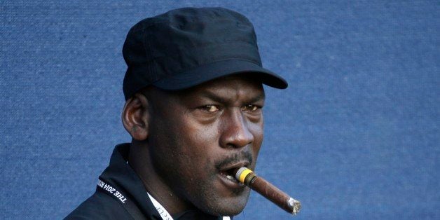 Basketball legend Michael Jordan smokes a cigar while watching the fourball match on the first day of the Ryder Cup golf tournament, at Gleneagles, Scotland, Friday, Sept. 26, 2014. (AP Photo/Matt Dunham)