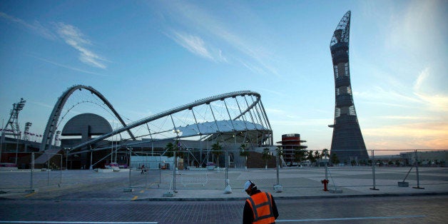 FILE- Advance to go with story slugged Qatar Labor Rights. In this Jan. 3, 2011 file photo, a worker cleans the road outside Khalifa sport complex in Doha, Qatar. Amnesty International said Wednesday, Nov. 12, 2014, that 2022 World Cup host nation Qatar is lagging behind on addressing concerns about the abuse of migrant workers six months after it laid out plans for labor reforms. Like other energy-rich Gulf nations, Qatar relies heavily on migrant workers drawn mainly from South Asia to build its roads, skyscrapers and stadiums. (AP Photo/Kin Cheung-file)