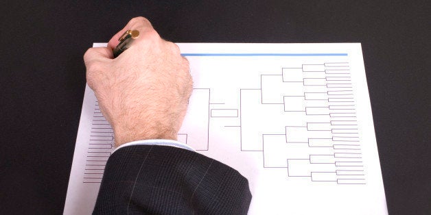 Closeup of a businessman's hand holding a pen completing tournament bracket