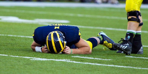In this Sept. 27, 2014, photo, Michigan quarterback Shane Morris lays on the field after taking a hit in the fourth quarter of an NCAA college football game against Michigan in Ann Arbor, Mich. Early Tuesday, Sept. 30, 2014, roughly 12 hours after embattled Michigan coach Brady Hoke said he'd been given no indication that Morris had been diagnosed with a concussion, athletic director Dave Brandon revealed in a post-midnight statement that the sophomore did appear to have sustained one. (AP Photo/Tony Ding)