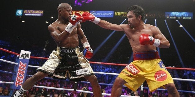 Floyd Mayweather Jr. exchange punches with Manny Pacquiao during their welterweight unification championship bout, May 2, 2015 at MGM Grand Garden Arena in Las Vegas, Nevada. Mayweather defeated Pacquiao by unanimous decision. AFP PHOTO / JOHN GURZINKSI (Photo credit should read JOHN GURZINSKI/AFP/Getty Images)