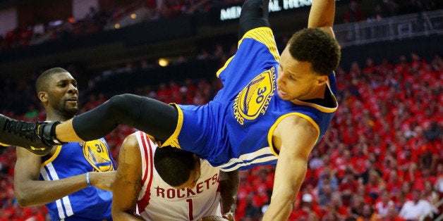 HOUSTON, TX - MAY 25: Stephen Curry #30 of the Golden State Warriors falls over Trevor Ariza #1 of the Houston Rockets on hi