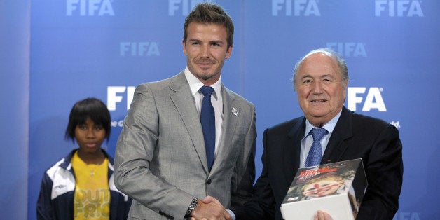 FIFA president Sepp Blatter (R) poses after receiving the bid books for 2018 and 2022 FIFA World Cups from former England football captain David Beckham (C) as Coaching for hope participant Nothemba Bambiso (L) looks on during an official handover ceremony at FIFA's headquarters on May 14, 2010 in Zurich. England star David Beckham, Dutch and Belgian footballing greats on bicycles, and a Japanese bid combining electronics with an origami popout opened the bidding to host the World Cup in 2018 or 2022. AFP PHOTO / FABRICE COFFRINI (Photo credit should read FABRICE COFFRINI/AFP/Getty Images)