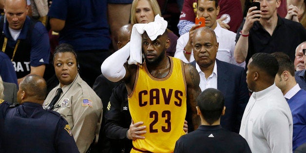 Cleveland Cavaliers forward LeBron James (23) holds a towel to his head after being knocked into the fans during the first half of Game 4 of basketball's NBA Finals against the Golden State Warriors in Cleveland, Thursday, June 11, 2015. (AP Photo/Paul Sancya)