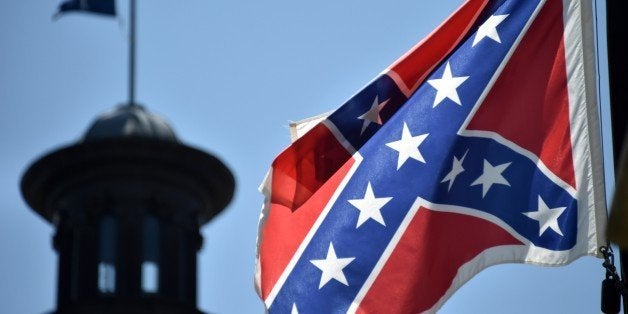 The South Carolina and American flags flying at half-staff behind the Confederate flag erected in front of the State Congress