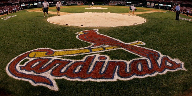 ST. LOUIS - OCTOBER 19: Stadium workers cover home plate with a tarp as security keeps a close eye on fans remaining in the