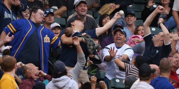 SEATTLE, WA - AUGUST 18: A fan cradling a baby reaches for a foul ball by Michael Saunders of the Seattle Mariners during th
