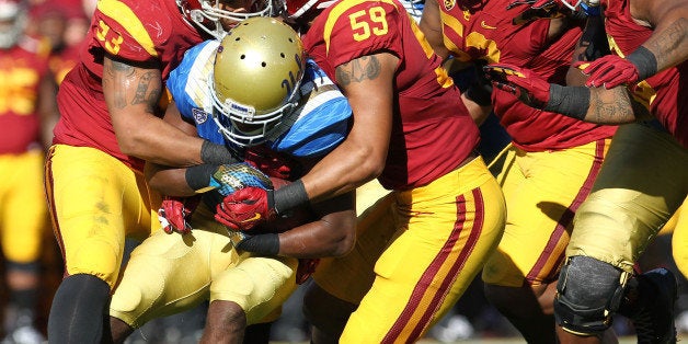 LOS ANGELES, CA - NOVEMBER 28: Paul Perkins #24 of the UCLA Bruins is tackled by the USC Trojan defense during a 40-21 Trojan win in a NCAA PAC12 college football game at Los Angeles Memorial Coliseum on November 28, 2015 in Los Angeles, California. (Photo by Leon Bennett/Getty Images)