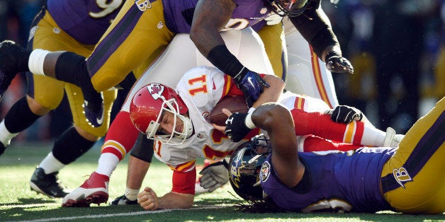 Kansas City Chiefs quarterback Alex Smith (11) gets tangled with Baltimore Ravens as he tries to protect the ball in the first half of an NFL football game, Sunday, Dec. 20, 2015, in Baltimore. (AP Photo/Gail Burton)