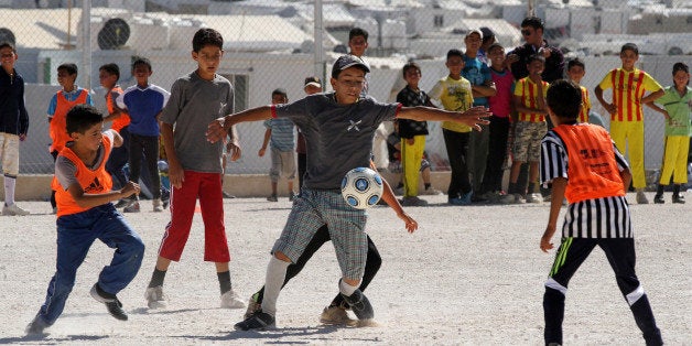 Syrian refugee children play soccer as others watch at the Zaatari refugee camp in Mafraq near the Syrian border in Jordan, Saturday, June 14, 2014. The soccer project, in conjunction with the World Cup in Brazil, was organized by the Asian Football Development Project, founded by Jordan's Prince Ali Bin al-Hussein, FIFA vice president, and the Union of European Football Associations. (AP Photo/Raad Adayleh)