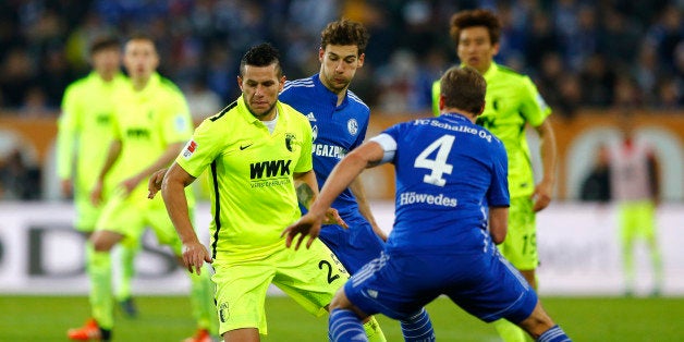 Augsburg's Raul Bobadilla, left, Schalke's Leon Goretzka, background, and Schalke's Benedikt Hoewedes challenge for the ball during the German Bundesliga soccer match between FC Augsburg and FC Schalke 04 at the WWK Arena stadium in Augsburg, Germany, Sunday, Dec. 13, 2015. (AP Photo/Matthias Schrader)