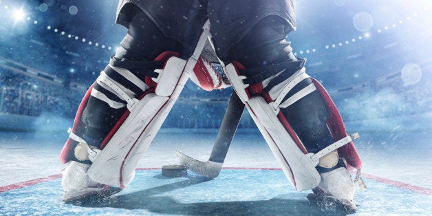 View of professional ice hockey goalie during game in indoor arena full of spectator