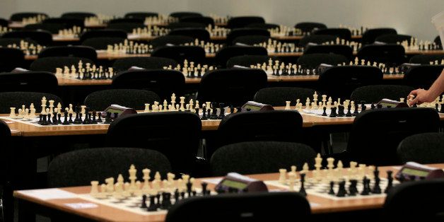 Tables are laid out with rows of chess boards as a member of staff puts out the final pieces prior to the start of the London Chess Classic tournament taking place over the weekend, in London, Friday, Dec. 4, 2015. (AP Photo/Alastair Grant)
