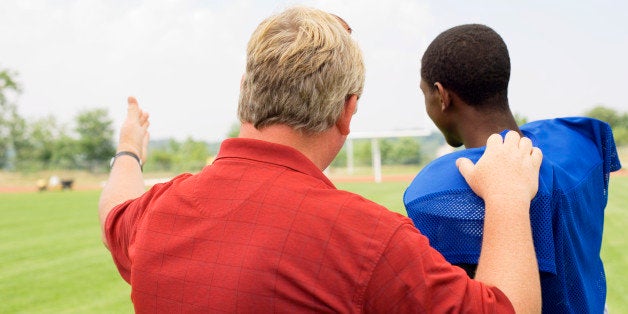 Coach talking to boy in football gear