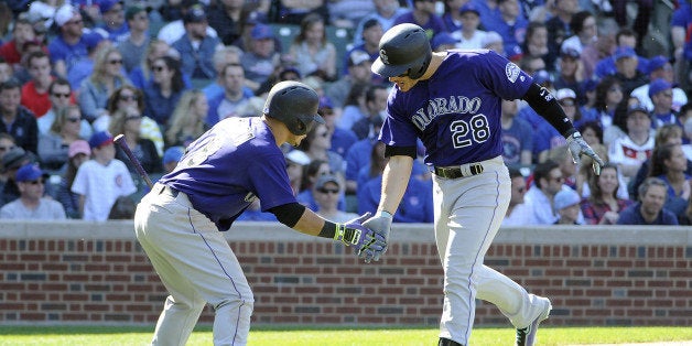 Colorado Rockies' Nolan Arenado (28) is greeted by teammate Gerardo Parra (8) after hitting a solo home run against the Chicago Cubs during the ninth inning of a baseball game, Sunday, April 17, 2016, in Chicago. (AP Photo/David Banks)