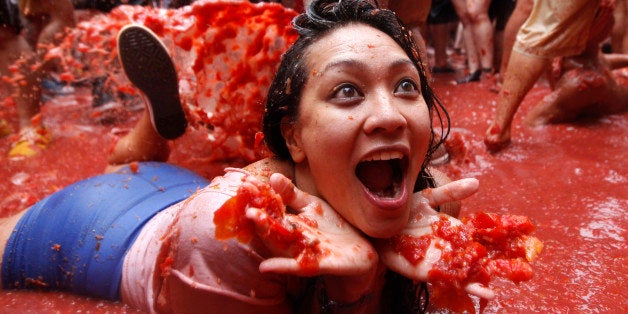 A woman lays on a puddle of tomato juice during the annual "tomatina" tomato fight fiesta in the village of