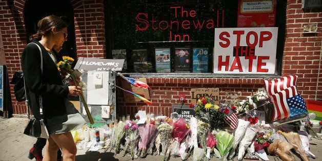 NEW YORK, NY - JUNE 13: Matti Mejia (hidden) and Shaina Roberts pause in front of the iconic gay and lesbian bar The Stonewall Inn to lay flowers and grieve for those killed in Orlando on June 13, 2016 in New York City. An American-born man who had recently pledged allegiance to ISIS killed 50 people early Sunday at a gay nightclub in Orlando, Florida. The massacre is the deadliest mass shooting in United States history. (Photo by Spencer Platt/Getty Images)