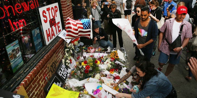 NEW YORK, NY - JUNE 13: People pause in front of the iconic New York City gay and lesbian bar The Stonewall Inn to lay flowers and grieve for those killed in Orlando on June 13, 2016 in New York City. An American-born man who had recently pledged allegiance to ISIS killed 50 people early Sunday at a gay nightclub in Orlando, Florida. The massacre is the deadliest mass shooting in United States history. (Photo by Spencer Platt/Getty Images)