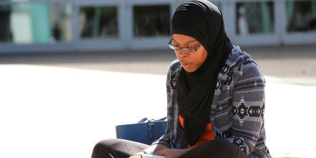 Tauhdedah El-Saadiq, of Louisville, reads a Koran while waiting for the ticket office to open for tickets to boxing legend Mu
