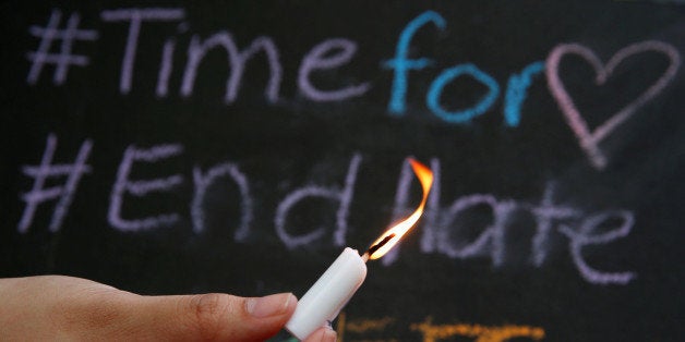 A University of the Philippines student holds a lit candle and a placard as a tribute to those killed in the Pulse nightclub mass shooting in Orlando, during a protest at the school campus in Quezon city, Metro Manila, Philippines June 14, 2016. REUTERS/Erik De Castro