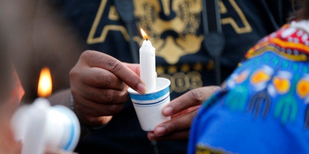 People hold candles at a vigil for Alton Sterling, who was shot and killed by a police, outside the Triple S convenience stor