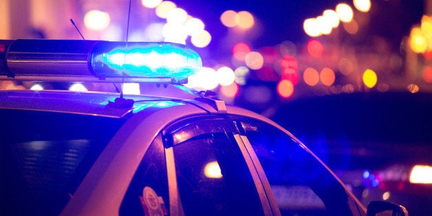 Blue light flasher atop of a police car. City lights on the background. 