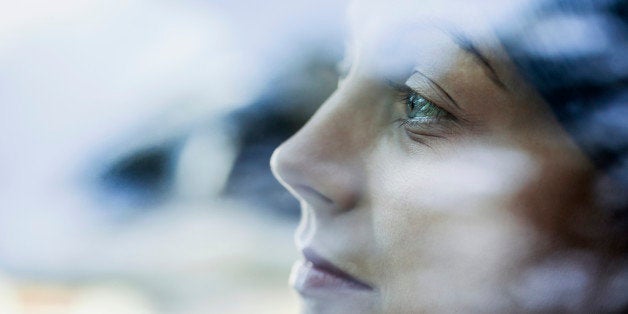 A young woman looking thoughtfully out the window of a stationary car