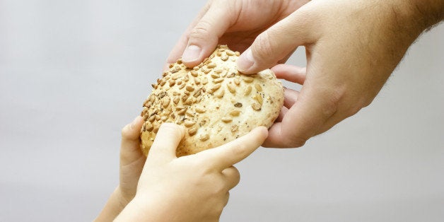 Sharing bread. Man giving bread to a small child. Charity concept.