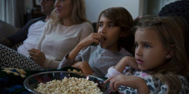 Family with popcorn watching movie in living room