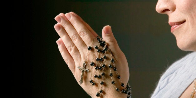 Woman praying with rosary beads