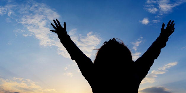 woman silhouette with arms raised praying.