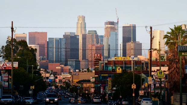As the sun rises across downtown Los Angeles, commuters on a section of Olympic Blvd in Koreatown are cast in shadow
