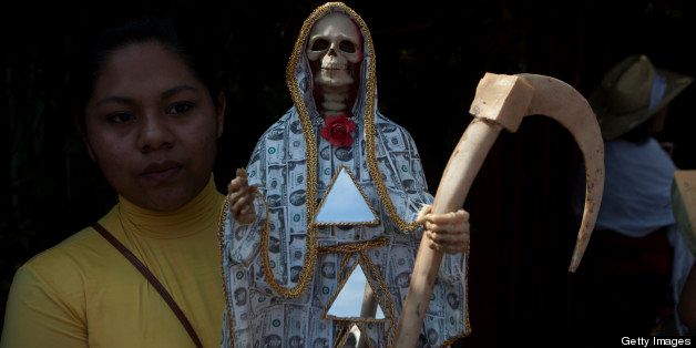 OAXACA, MEXICO - NOVEMBER 2: A woman carries a skeletal figure representing the folk saint known in Mexico as 'Santa Muerte' or ' Death Saint' during a procession in Oaxaca, Mexico on November 2, 2012 . ( Photo by Claudio Cruz/LatinContent/Getty Images)