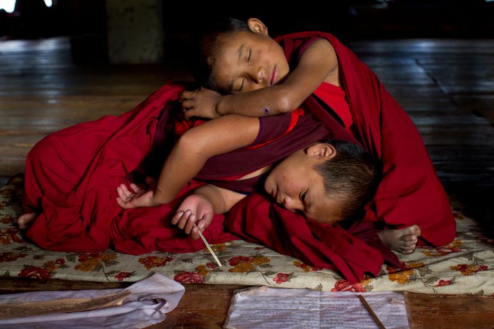 THIMPHU, BHUTAN - OCTOBER 18: Sangey, 6, and Tenzin, 7, rest after hours of prayer at the Dechen Phodrang monastery October 18, 2011 in Thimphu, Bhutan. About 375 monks reside at the government run monastery that also doubles as a child care facility for under privileged and orphaned males. The monks average about 10 hours of study a day waking up at 5:00am. Mahayana Buddhism is the state religion, although in the southern areas many citizens openly practice Hinduism. Monks join the monastery at six to nine years of age and according to tradition many families will send one son into the monk hood. They learn to read chhokey, the language of the ancient sacred texts, as well as Dzongkha and English. (Photo by Paula Bronstein/Getty Images)